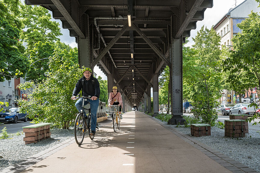 Reallabor Radbahn Zwei Radfahrende fahren auf der Teststrecke der Radbahn unter der U-Bahntrasse in Berlin.
